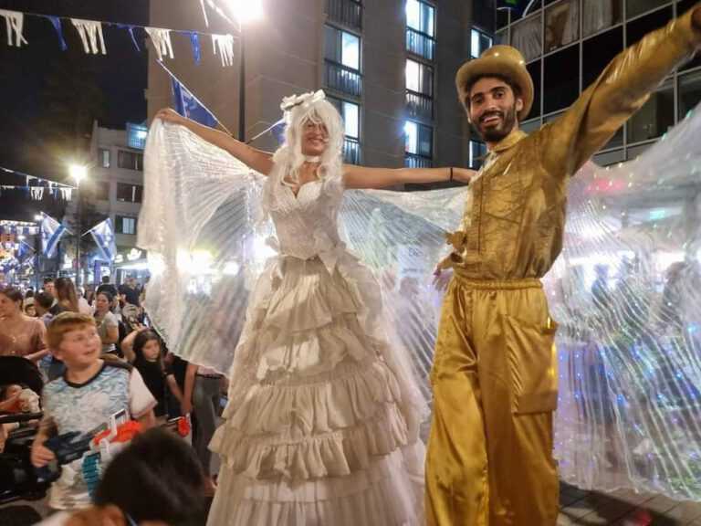 שתי דמויות קרקסיות על קביים במופע רחוב